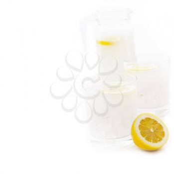 fresh lemonade drink with lemon slice closeup and pitcher carafe isolated