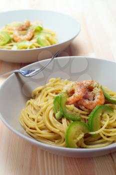 spaghetti pasta with fresh shrimps and zucchini sauce over wood table