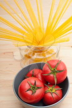 fresh tomato and raw spaghetti pasta over pine wood table