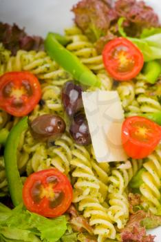 fresh healthy homemade italian fusilli pasta salad with parmesan cheese,pachino cherry tomatoes, black olives and mix vegetables ,dressed with extra-virgin olive oil and pesto sauce