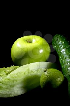 group of green vegetables and fruits over black background