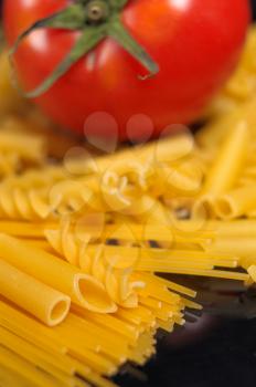 Italian pasta selection with fresh tomato over black closeup DOF