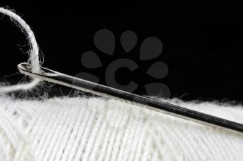 macro shot of needle and thread over black background