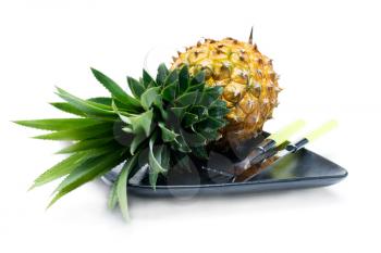 pineapple on a black plate with knife and fork isolated on white background