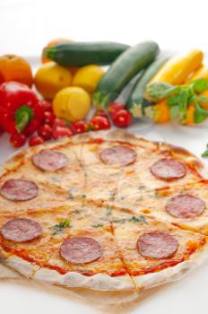 Italian original thin crust pepperoni pizza with fresh vegetables on background