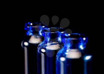 blue glass vials over black background backlit