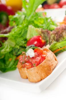 original Italian fresh bruschetta,typical finger food, with fresh salad and vegetables on background