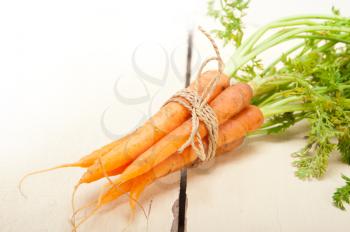 fresh baby carrots bunch tied with rope on a rustic table