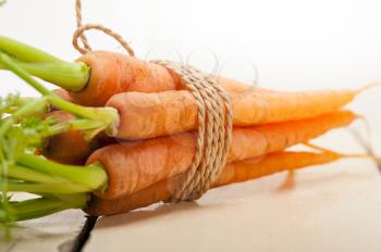 fresh baby carrots bunch tied with rope on a rustic table