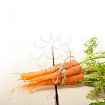 fresh baby carrots bunch tied with rope on a rustic table