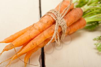 fresh baby carrots bunch tied with rope on a rustic table