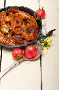 fresh seafood stew prepared on an iron skillet ove white rustic wood table 