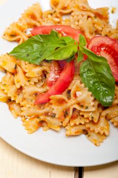 Italian pasta farfalle butterfly bow-tie with tomato basil sauce over white rustic wood table