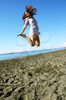 Royalty Free Photo of a Woman Jumping into the Air at the Beach