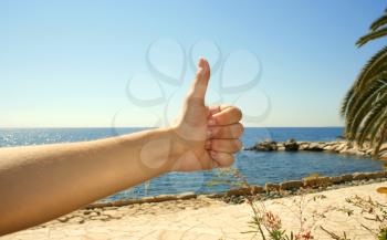 Royalty Free Photo of a Person Giving a Thumbs Up to a Beach