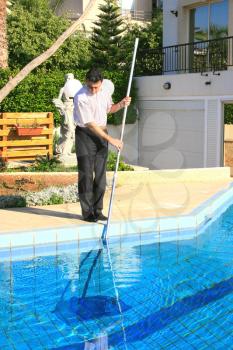 Royalty Free Photo of a Man Cleaning a Swimming Pool