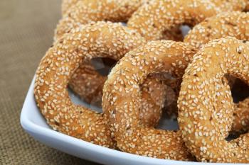 Round rusks with sesame seeads in white bowl.