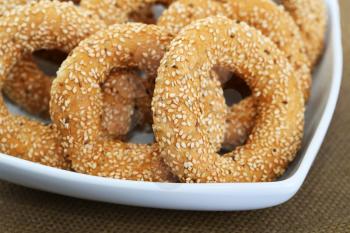 Round rusks with sesame seeads in white bowl.