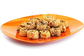 Rusks with sesame seeds and olives on orange plate isolated on white background.