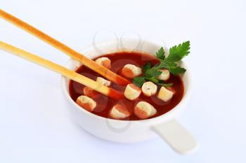 Croutons and bread sticks in red sauce on gray background.