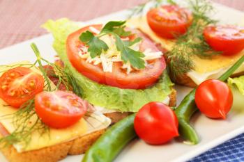 Sandwiches with bacon, cheese, cherry tomato and dill on plate.