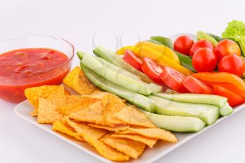 Nachos,  cheese sauce, vegetables isolated on gray background.