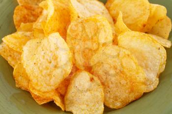 Potato chips on green plate, closeup image.