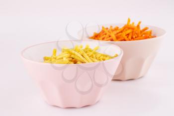 Potato chips in pink and beige bowls isolated on gray background.