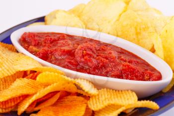 Potato chips and red sauce closeup image.