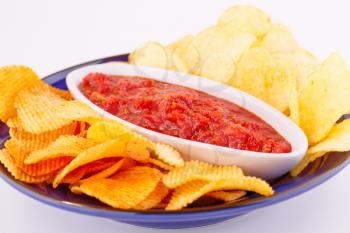 Potato chips and red sauce on plate isolated on gray background.