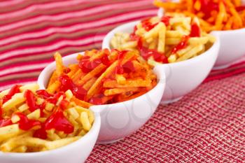 Potato chips with ketchup isolated on colorful tablecloth.