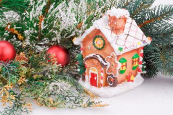 Christmas decoration with red balls, fir-tree branch and toy house.