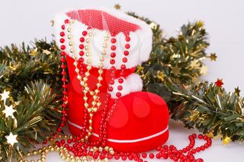 Christmas decoration with Santa's red boot and green garland on gray background.