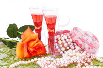 Two glasses, rose, colorful pearls necklaces and gift box on white background.