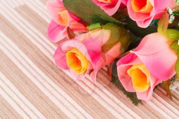 Colorful fabric roses on cloth background, closeup picture.