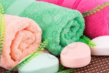 Colorful rolled towels with leaves and soaps closeup picture.