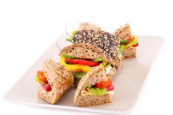 Sandwich with fresh vegetables, salami and cheese on plate.