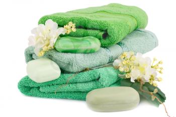 Folded towels, soaps and flowers isolated on white background.