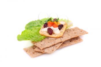 Crackers stacks with fresh vegetables and cream isolated on white background.