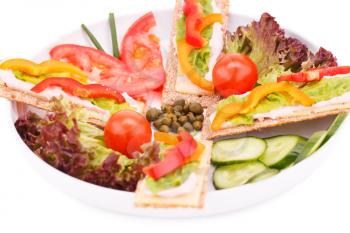 Crackers with fresh vegetables and cheese on round plate.