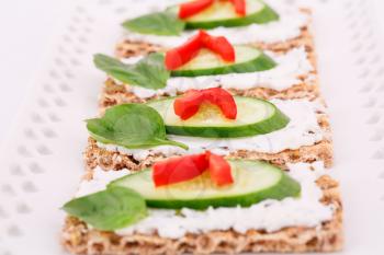 Cracker with fresh vegetables and cream on plate.