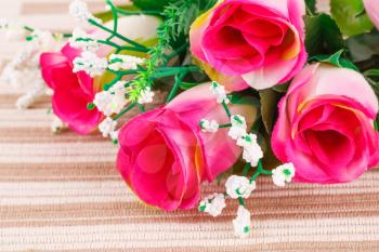 Pink fabric roses on beige cloth background.
