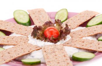 Cracker with fresh vegetables and cream on pink plate.