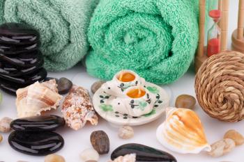 Spa set with towels, candles, shells, sandglass and stones closeup picture.