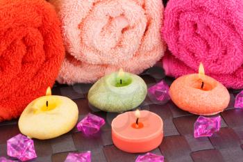 Spa set with towels, candles and stones on bamboo background.