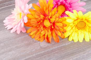 Colorful fabric daisies on wooden background.
