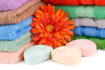 Colorful towels stacks, flower and soaps closeup picture.
