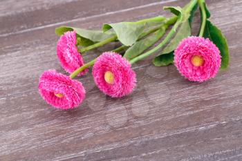 Pink fabric flowers on wooden background.