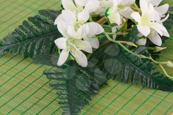 White fabric flowers on bamboo background, closeup picture.
