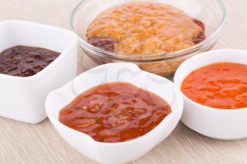 Different sauces in saucers on beige cloth background.